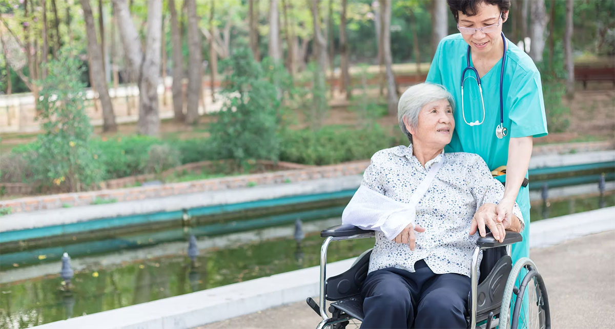 Staff and care worker wheeling resident in wheelchair